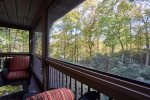 The view from the screened in porch is wooded and filled with rhododendrons.